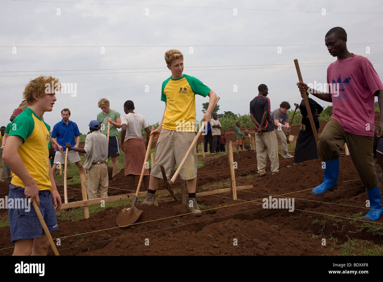 Zwei englische öffentliche Schüler helfen Einheimischen aus dem Dorf Kayonza in Ruanda ein Graben für eine neue Halle. Stockfoto