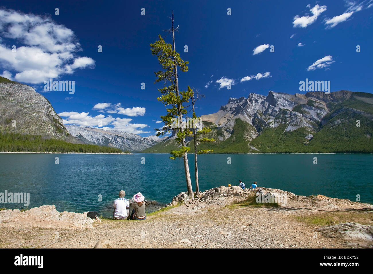 Junges Paar sitzt am felsigen Ufer.  Lake Minnewanka, Banff Nationalpark, Alberta, Kanada. Stockfoto