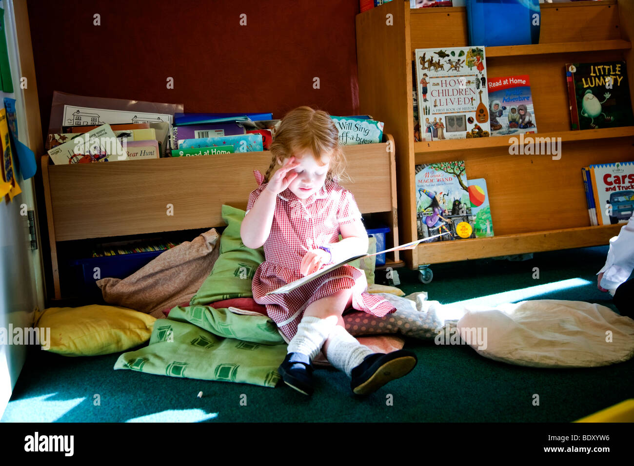 Mädchen lesen ein Buch allein in einem Klassenzimmer Stockfoto