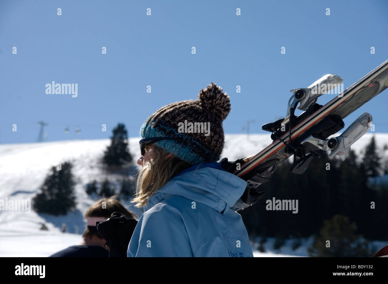 Skifahrer tragen eine Pudelmütze und Sonnenbrillen, tragen ihre Ski zum Sessellift. Courcheval, Frankreich Stockfoto