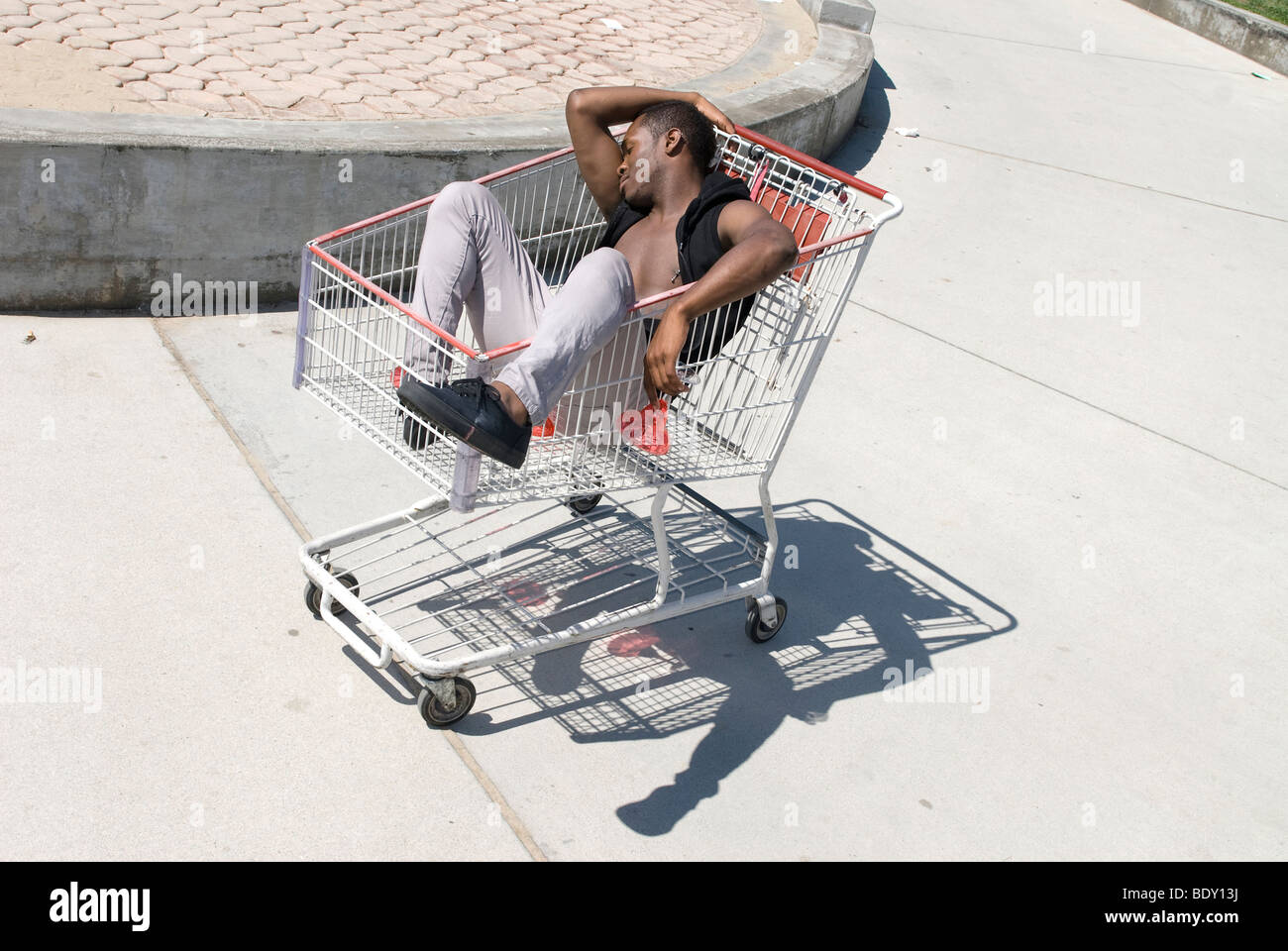 Afro-Amerikaner ist in einem Warenkorb nach einer exzessiven Party ohnmächtig. Stockfoto