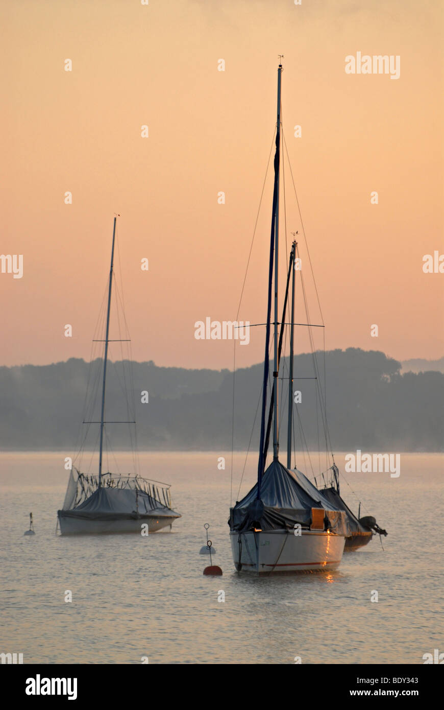 Das erste Licht des Tages trifft Segelboote am Ammersee in der Nähe von Schondorf, Bayern, Deutschland, Europa Stockfoto