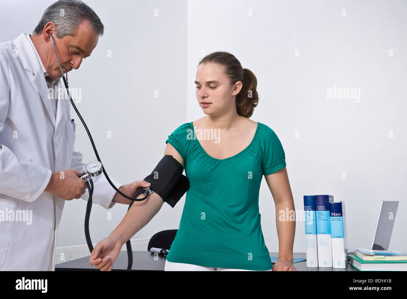 Arzt den Blutdruck eines jungen Patienten messen Stockfoto