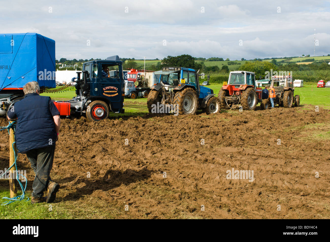 Landwirtschaftliche Zugmaschinen Abschleppen von LKW durch einen schlammigen Feld Stockfoto