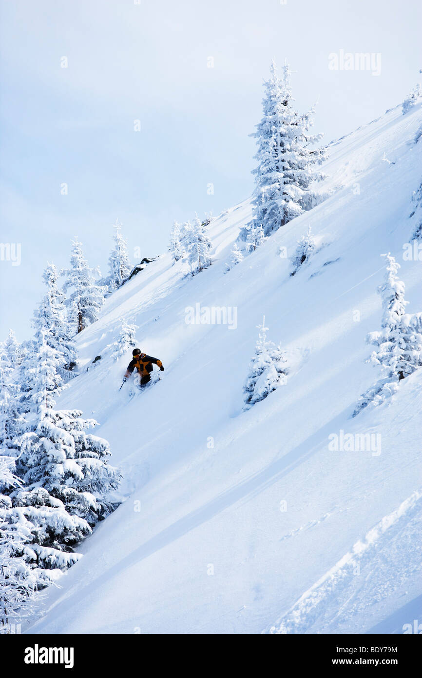 Mann in schwarz & orange Outfit abseits der Piste. Stockfoto