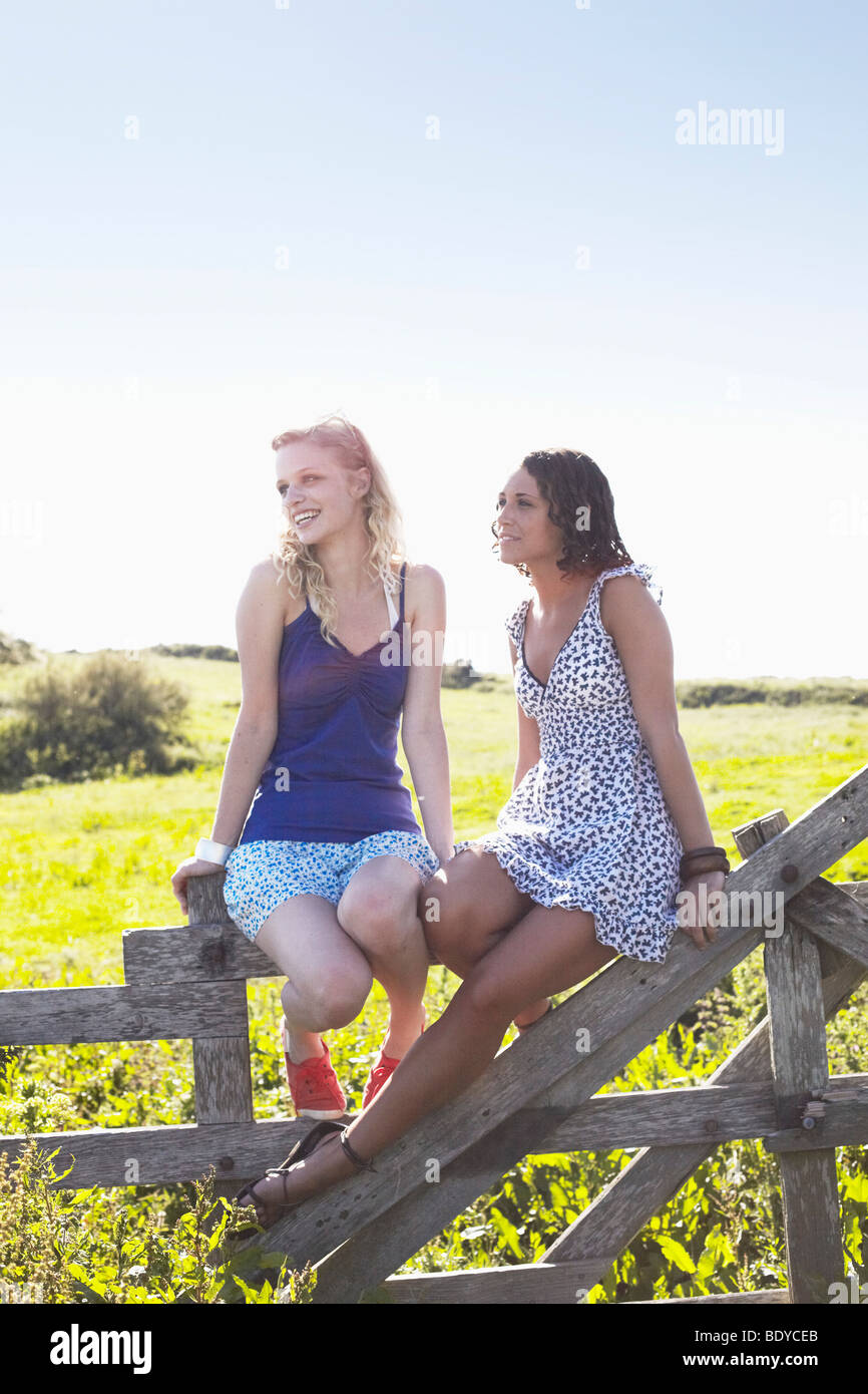 zwei Mädchen sitzen auf einem Zaun Stockfoto