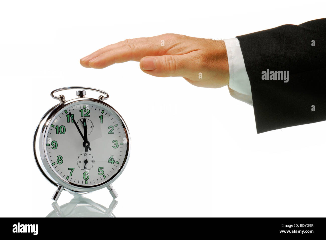 Business-Mann Hand mit einem Wecker einstellen bei 5 bis 12, kurz vor zwölf Uhr mittags, symbolisches Bild für die Aktion in einer Krise Stockfoto