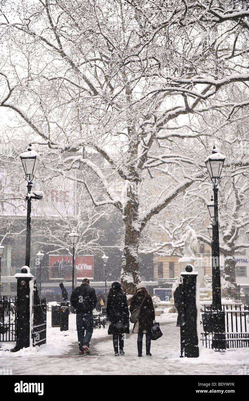 Drei Personen zu Fuß durch Leicester Square, London, im Schnee. Stockfoto