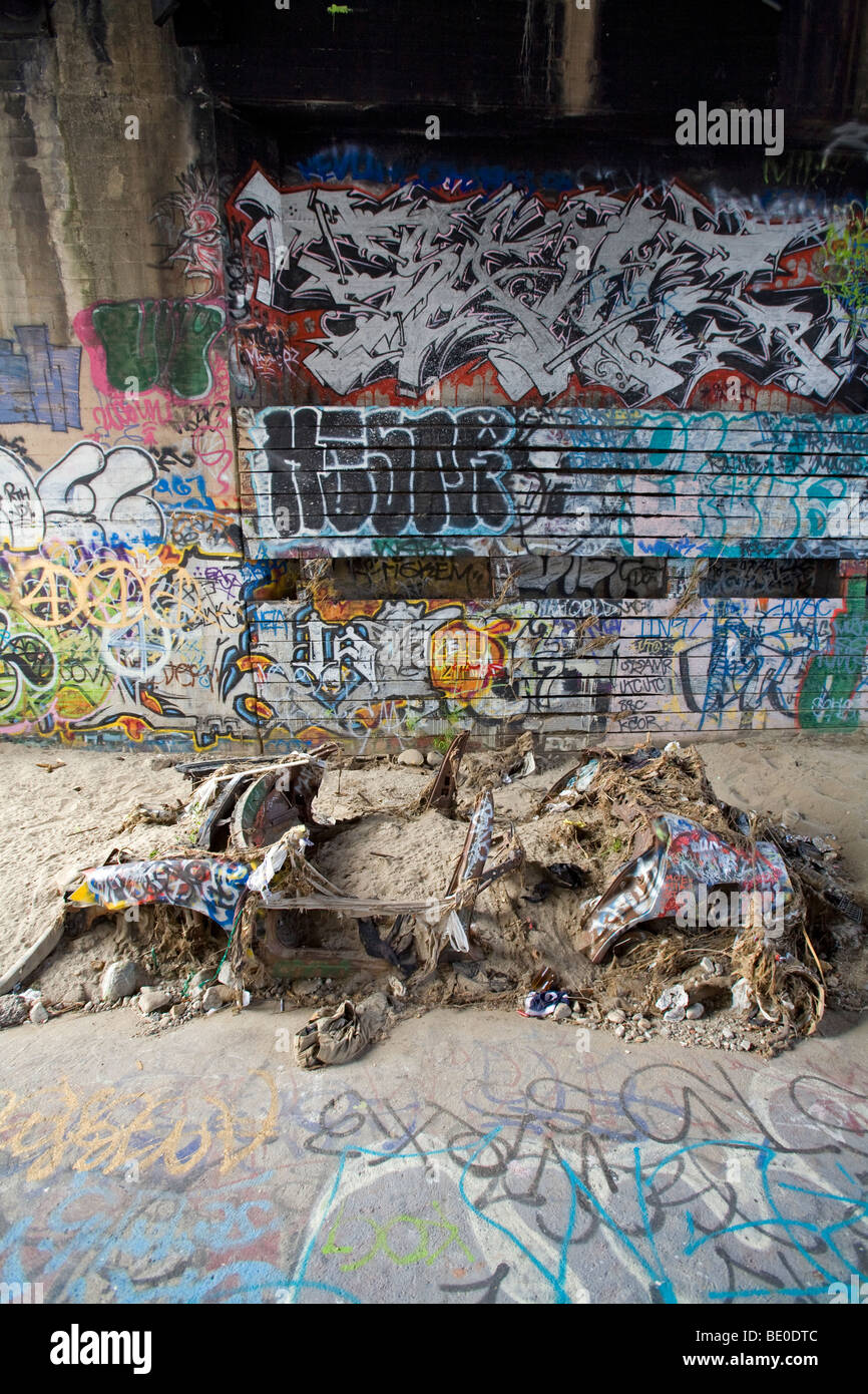 Verlassenes Auto und Graffiti unter Brücke in Los Angeles River, Kalifornien, USA. Stockfoto