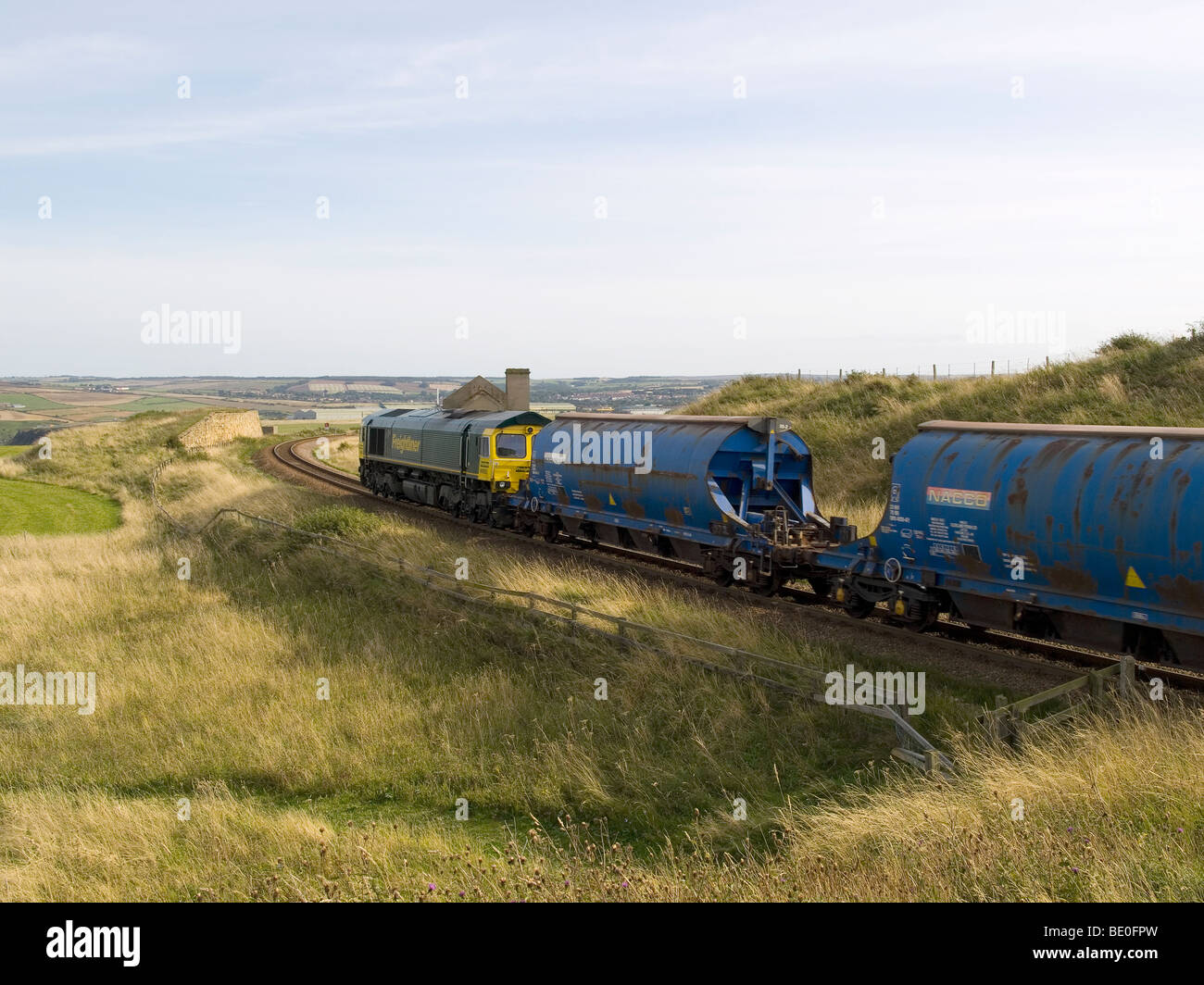 Ein Zug in Richtung der Cleveland Potash Mine bei Boulby vorbei die Hausruine Guibal Fan vom ehemaligen Huntcliff Eisen Bergwerk Stockfoto