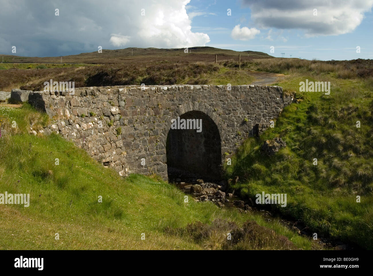 Alten Trockenmauern Brücke mit einem Bogen in den Hügeln von der Isle Of Skye genannt die Feenbrücke mit bedrohlichen Wolke dahinter Stockfoto