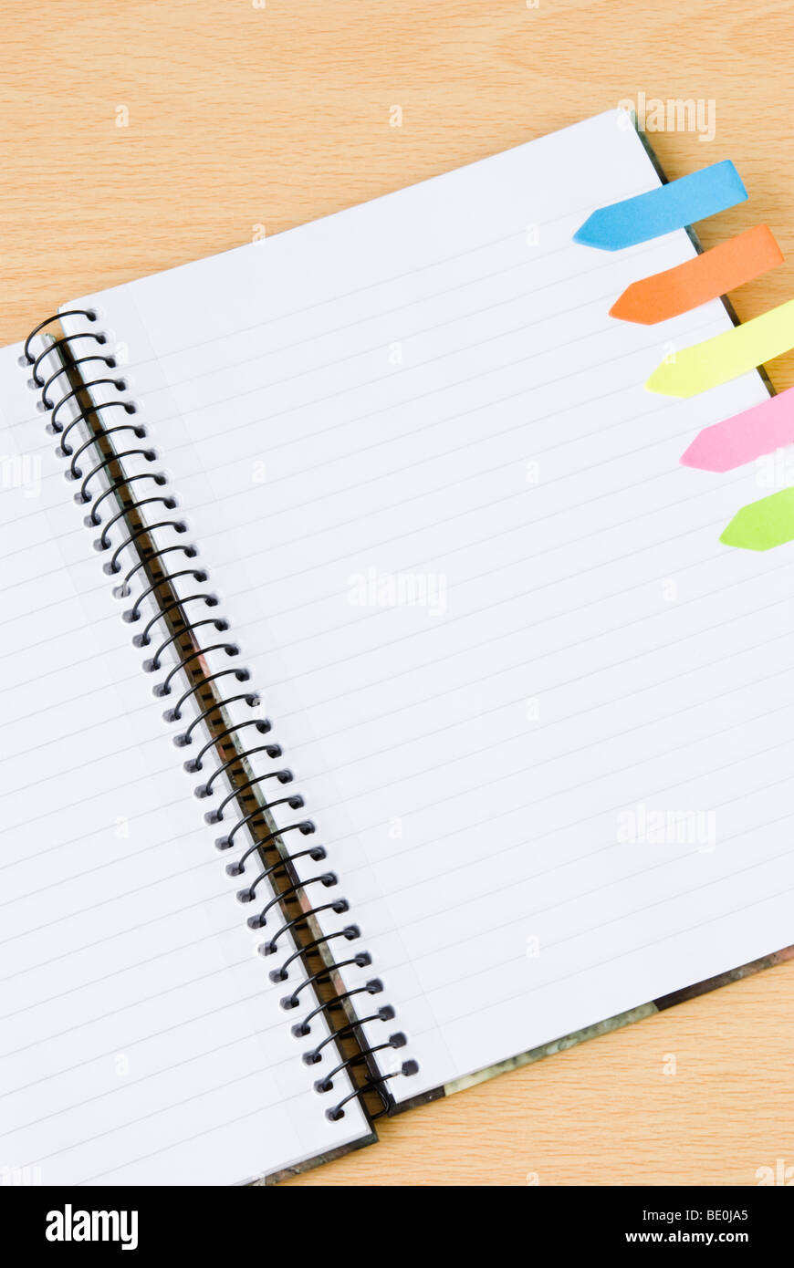 Gefütterte Spirale Notizblock mit bunten Postit Haftnotizen auf hölzernen Hintergrund isoliert Stockfoto
