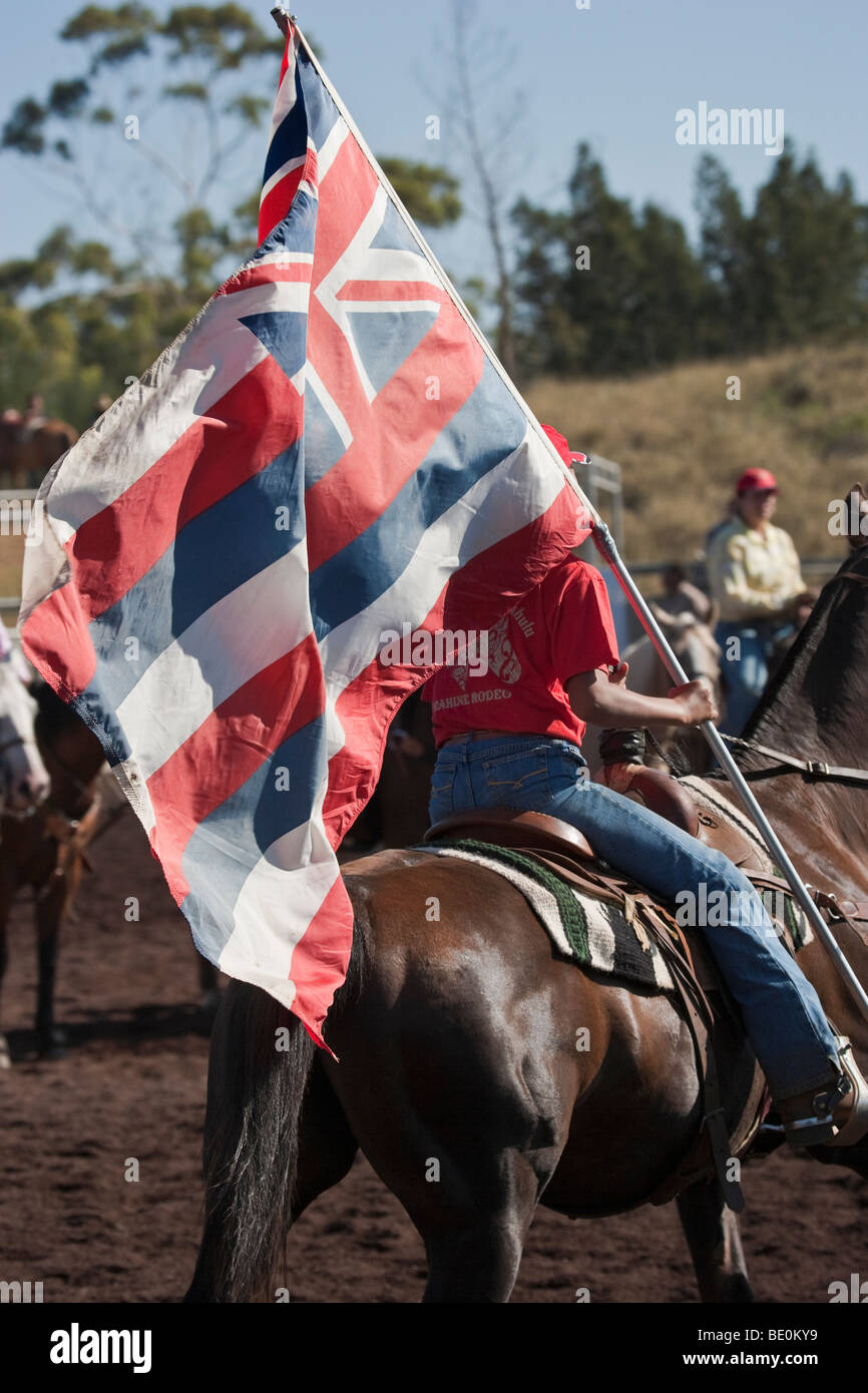 Weibliche Rodeo-Reiter Paraden hawaiischen Flagge. Stockfoto