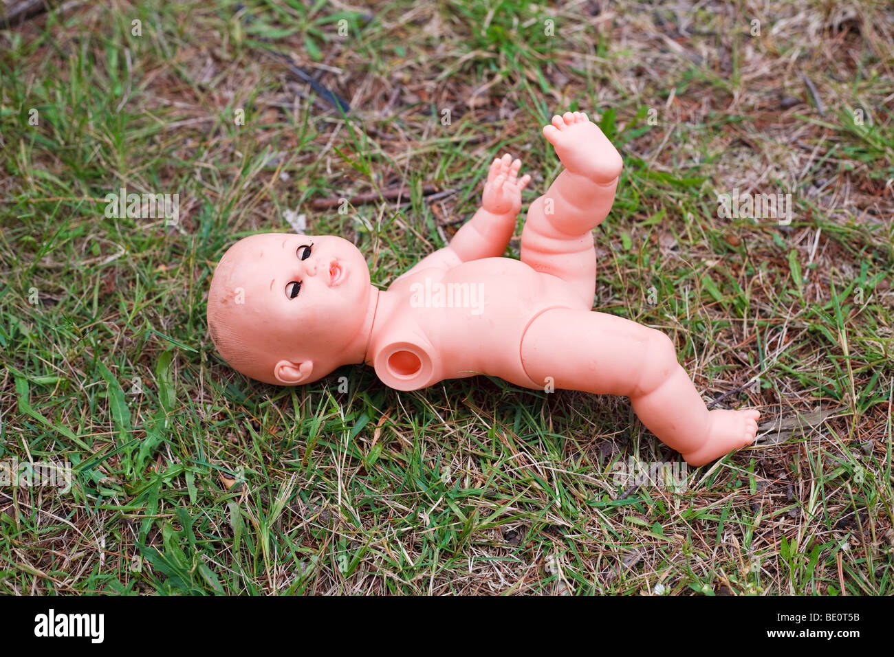 Verlassene und gebrochene Babypuppe mit eine Hand fehlt n den Rasen verlegen Stockfoto