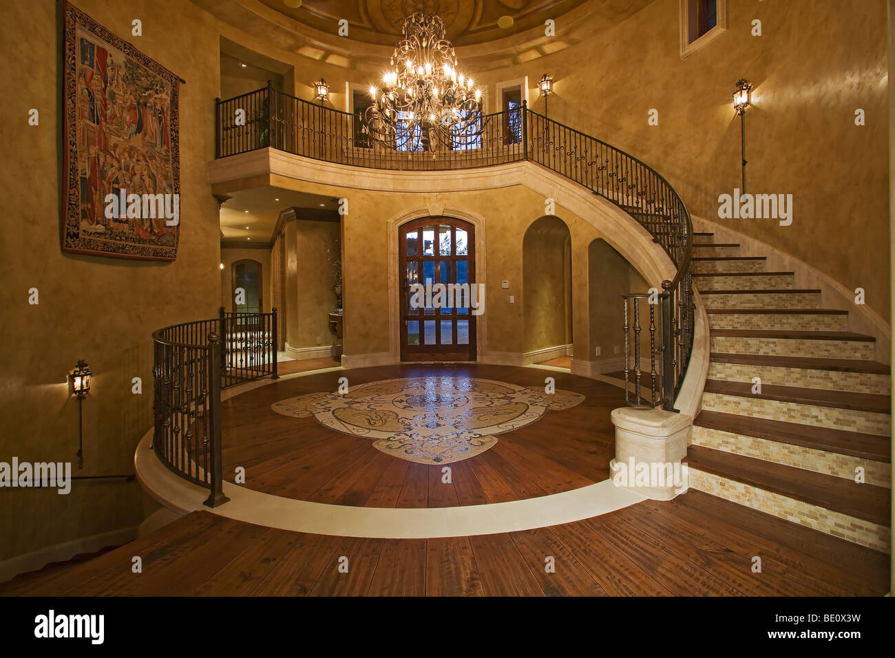 Atemberaubende faux-fertige Decke sieht man im großen Foyer mit geschwungene Treppe, Holzböden und große Kronleuchter Stockfoto