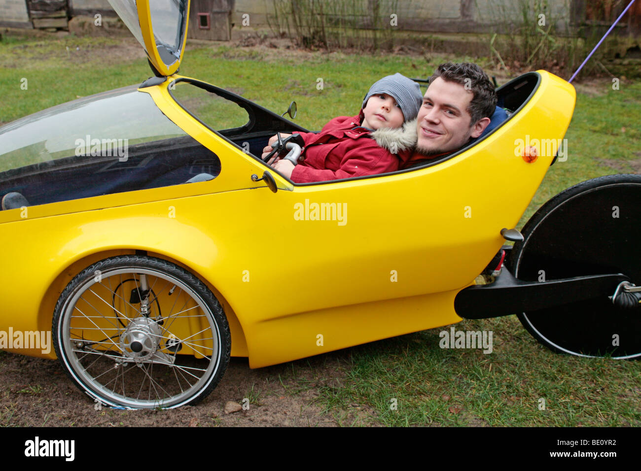 Porträt eines Vaters und seines kleinen Sohnes zusammen in einem selbstgebauten Elektromobil Stockfoto