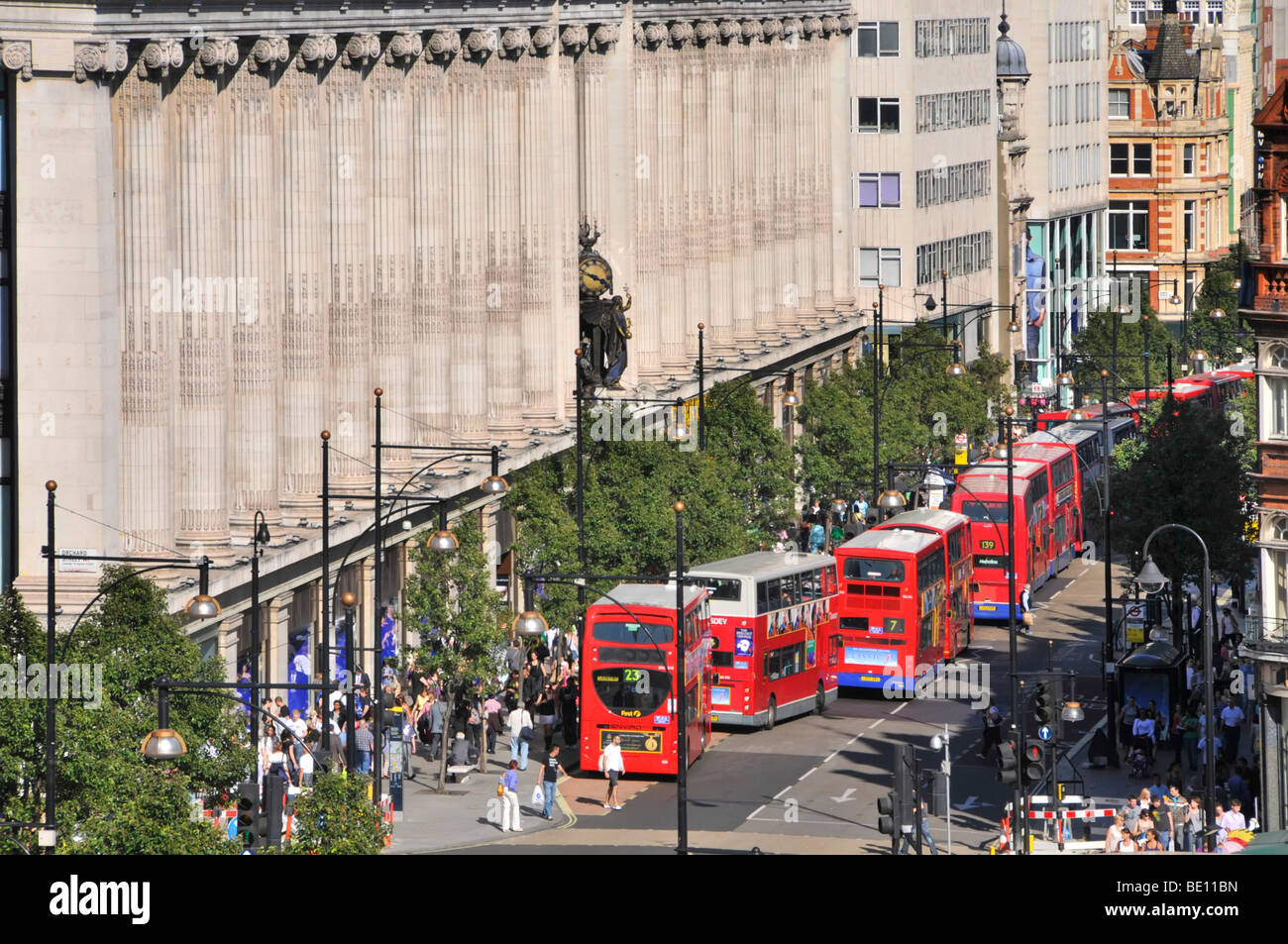 Oxford Street-Fassade des Kaufhauses Selfridges mit langen Schlange Doppel Decker roten Londoner Busse an Bushaltestellen & Kreuzungen Stockfoto