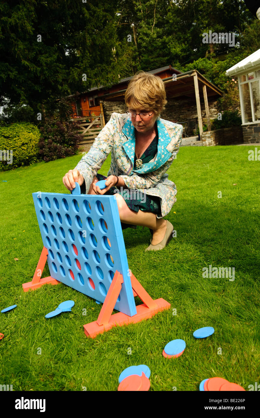 Frau spielt eine riesige Version von Connect 4 in einem Garten auf einem Sommer Nachmittag UK Stockfoto