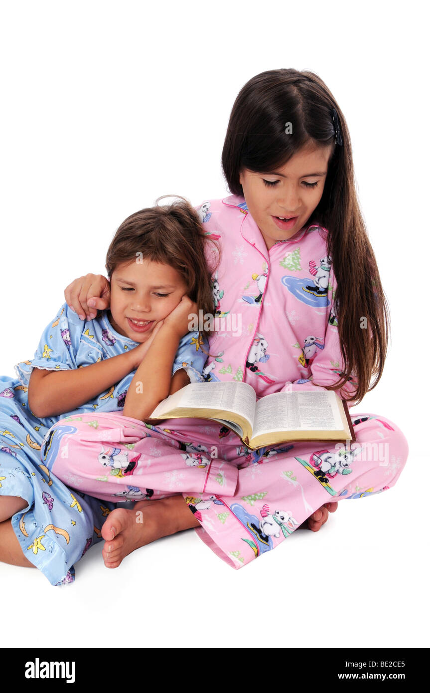 Mädchen lesen die Bibel als eine Gutenachtgeschichte zu Schwester Stockfoto