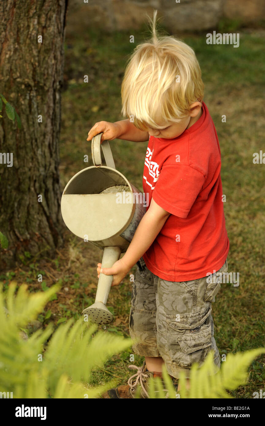 Ein drei Jahre alter Junge spielt mit einem Outdoor-Vintage Hand Wasser Pumpe Garten Stockfoto