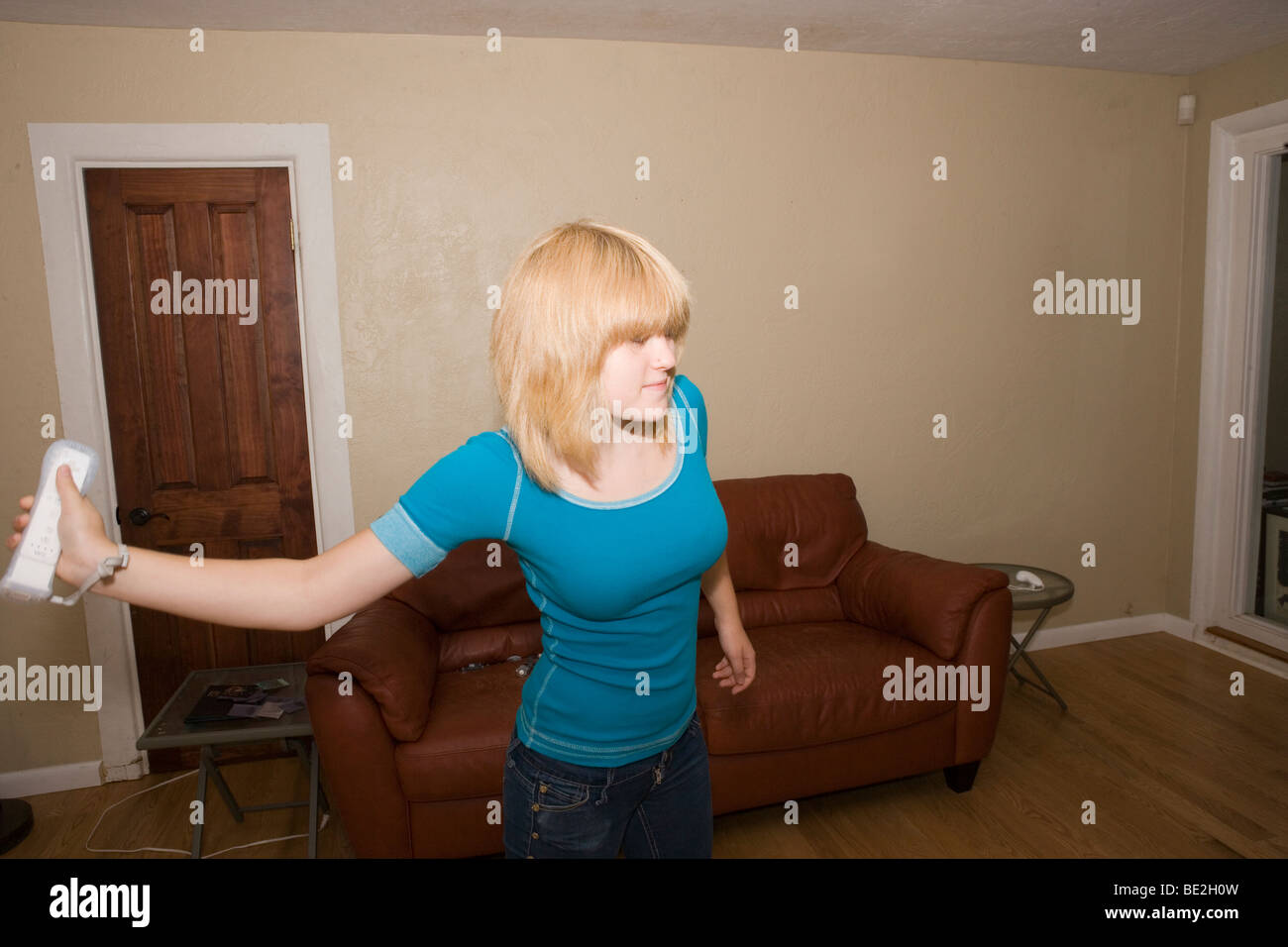 Teenager-Mädchen schwingt ihr Arm während des Spielens einer Wii Sportspiel zu Hause Stockfoto