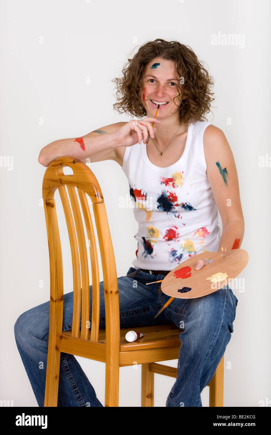 Künstler auf einem Stuhl sitzend, hält eine Pinsel und Farbpalette, lachen Stockfoto