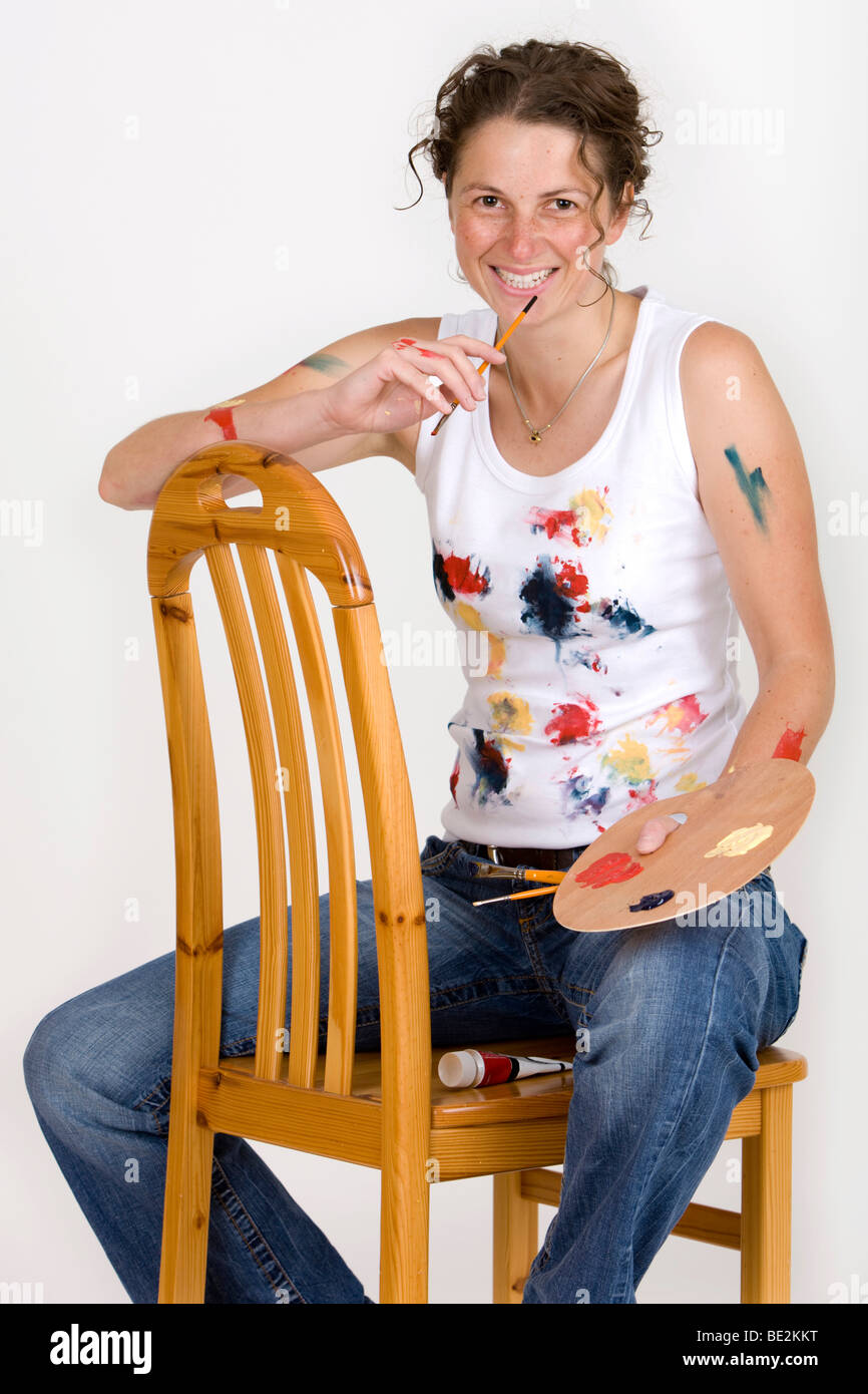 Künstler auf einem Stuhl sitzend, hält eine Pinsel und Farbpalette, lachen Stockfoto