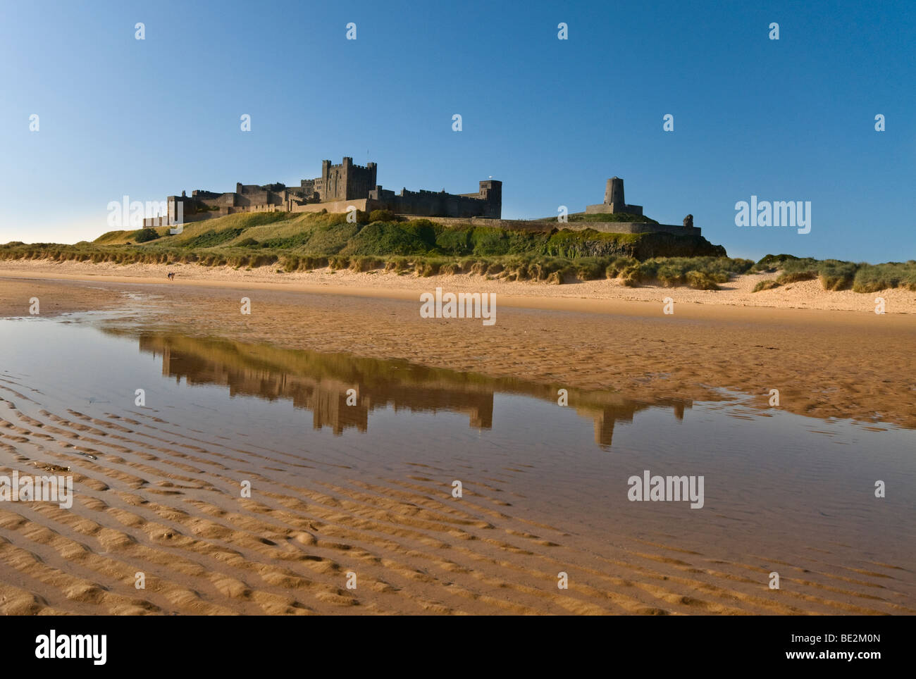 Imposante Bamburgh Castle spiegelt sich in einem Pool von Meerwasser Stockfoto