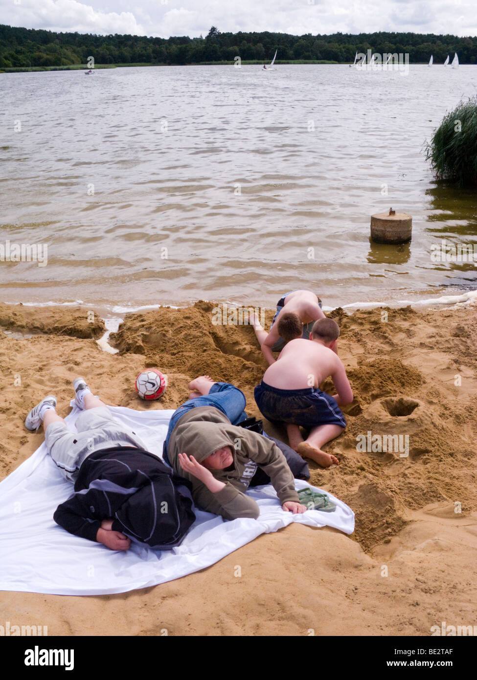 Jungen spielen am Strand durch das Wasser am großen Teich Frensham. Churt, in der Nähe von Farnham, Surrey. VEREINIGTES KÖNIGREICH. Stockfoto