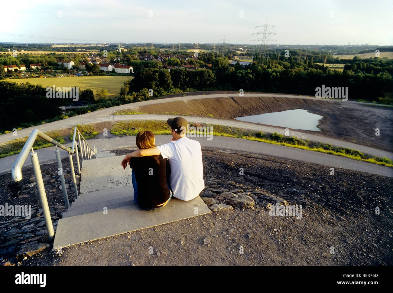 Junges Paar sitzt auf einer Treppe mit Blick auf eine desolate Vorrat Landschaft, Halde Rheinelbe Dump, Gelsenkirchen-Ueckendorf, Stockfoto