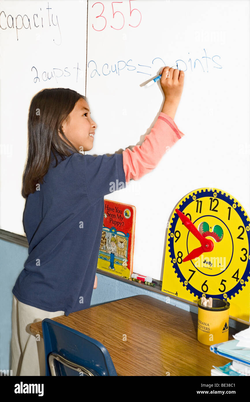 Eine vietnamesische American 7 + Studentin schreibt am Whiteboard im Unterricht. Stockfoto