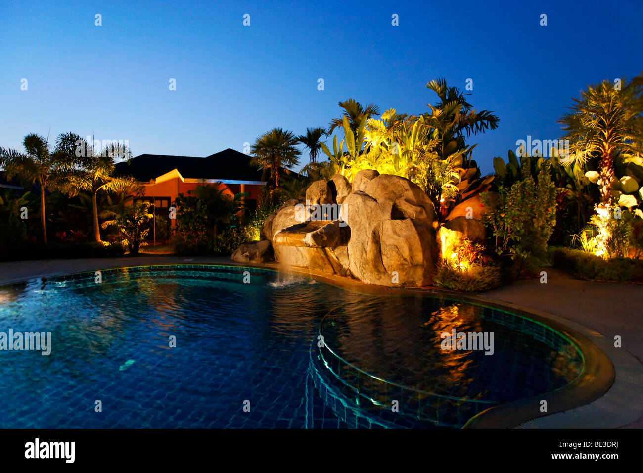 Beleuchtete Bungalow mit grünen, künstlichen Wasserfall und Pool in der Dämmerung, Palm Garden Resort, Khao Lak, Phuket, Thail Stockfoto