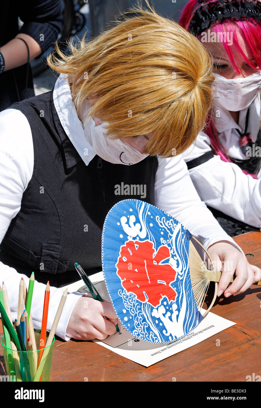 Teen lösen einer Aufgabe, Schutz der Antwort mit einem japanischen Fan vor neugierigen Augen, Manga-Wettbewerb, Japan Tag, Düsseldorf, NRW Stockfoto