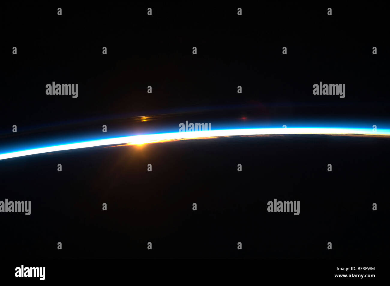 Die dünne Linie der Erdatmosphäre und die aufgehende Sonne. Stockfoto