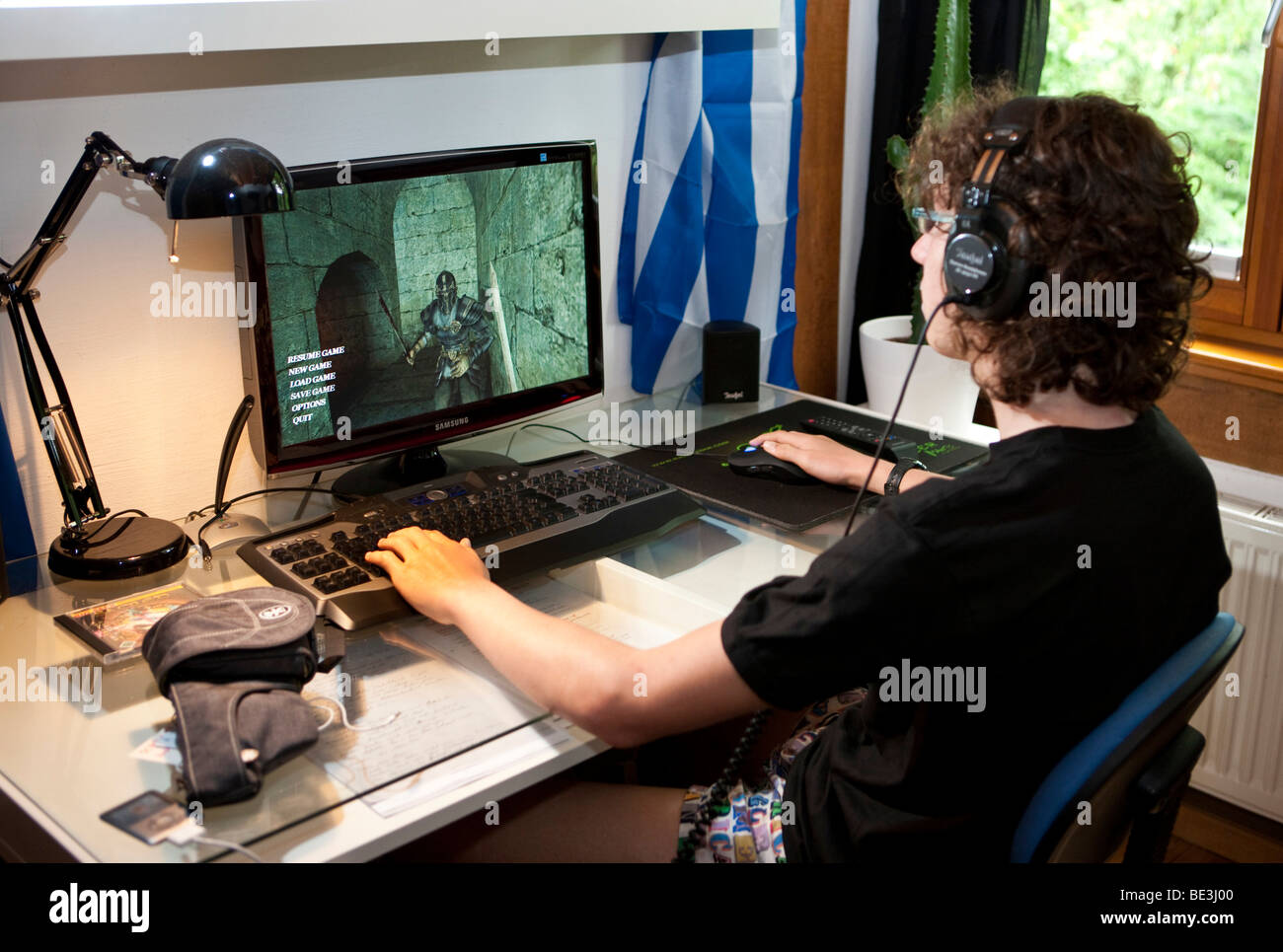 Ein Junge, ca. 15, spielt ein gewaltfreies Spiel auf dem Computer in seinem Raum, Deutschland, Europa Stockfoto