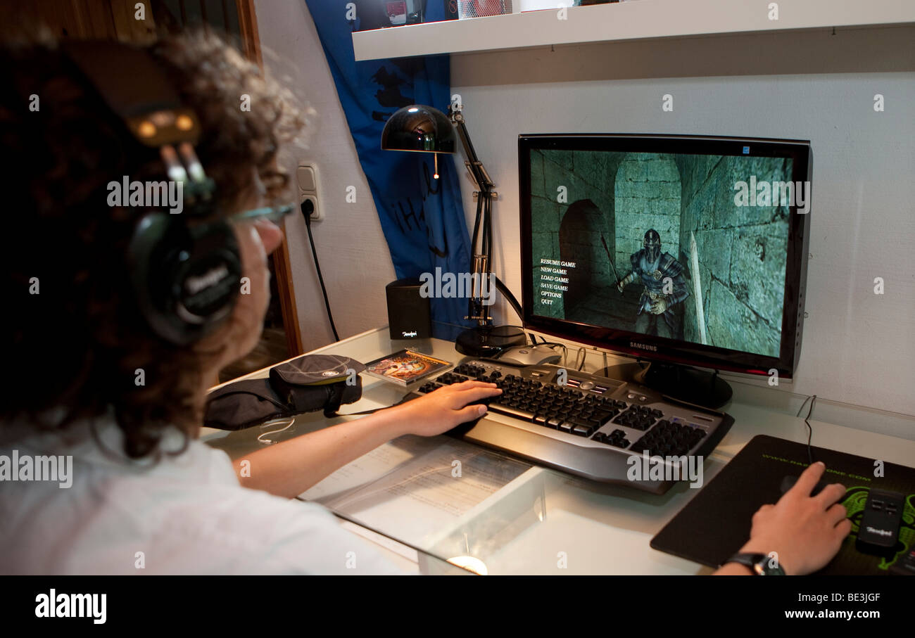 Ein Junge, ca. 15, spielt ein gewaltfreies Spiel auf dem Computer in seinem Raum, Deutschland, Europa Stockfoto