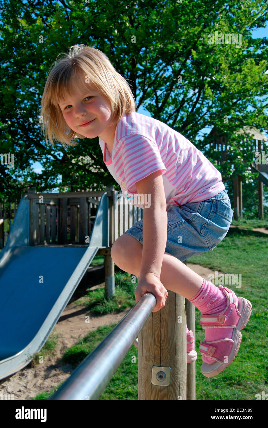 Blonde Mädchen, 5 Jahre, Klettern auf einem Klettergerüst Stockfoto