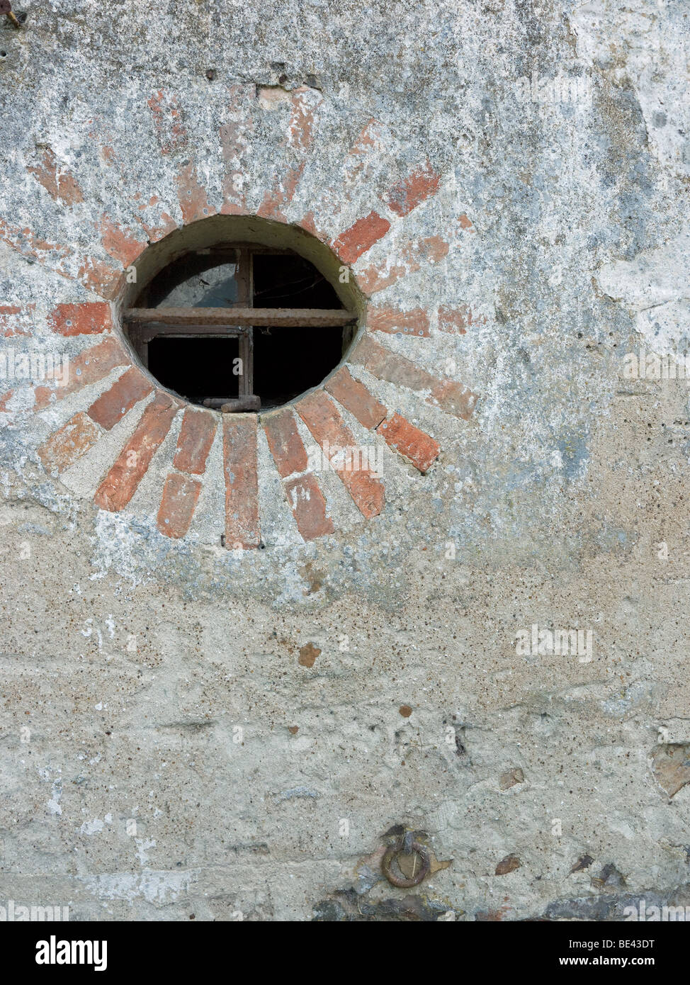 Ein rundes Fenster in einer alten französischen Mühle schafft eine Sonne wie Muster. Stockfoto