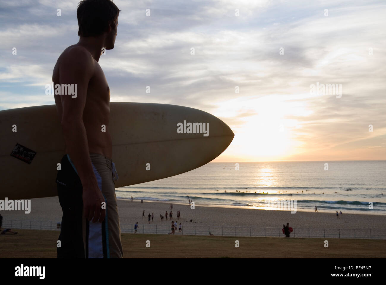 Mann mit Surfbrett auf den Strand bei Sonnenaufgang. Bondi Beach, Sydney, New South Wales, Australien Stockfoto