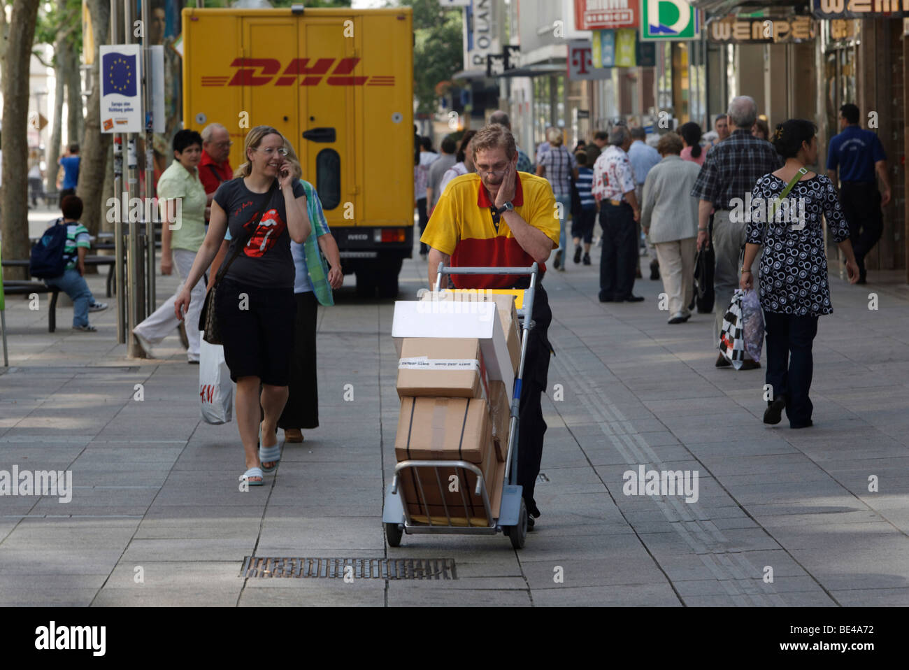 Paket-Träger Michael Meindel Ausgleich einen Stapel von Paketen auf der anderen Straßenseite mit seinem Karren für die Deutsche Post Deutsche Post Stockfoto
