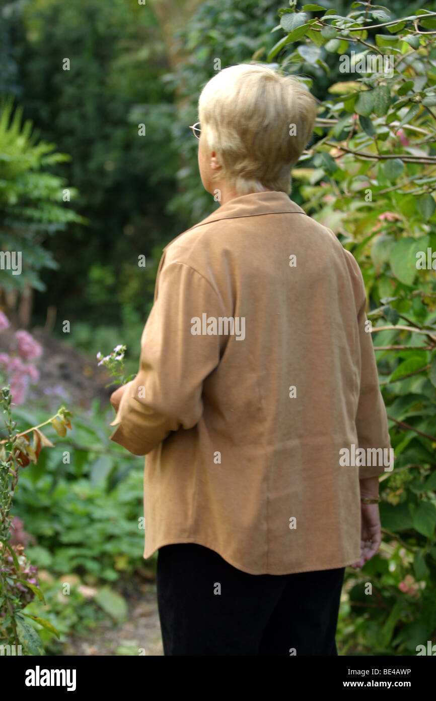 Rückansicht senior Frau im Garten draußen, möglicherweise verloren oder verwirrt Oap. Stockfoto