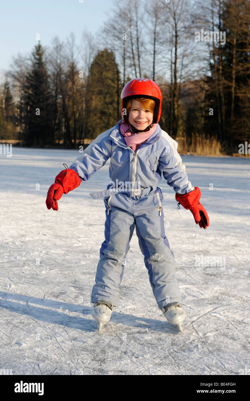 Mädchen das Tragen eines Helmes Eislaufen auf einem kleinen See Stockfoto