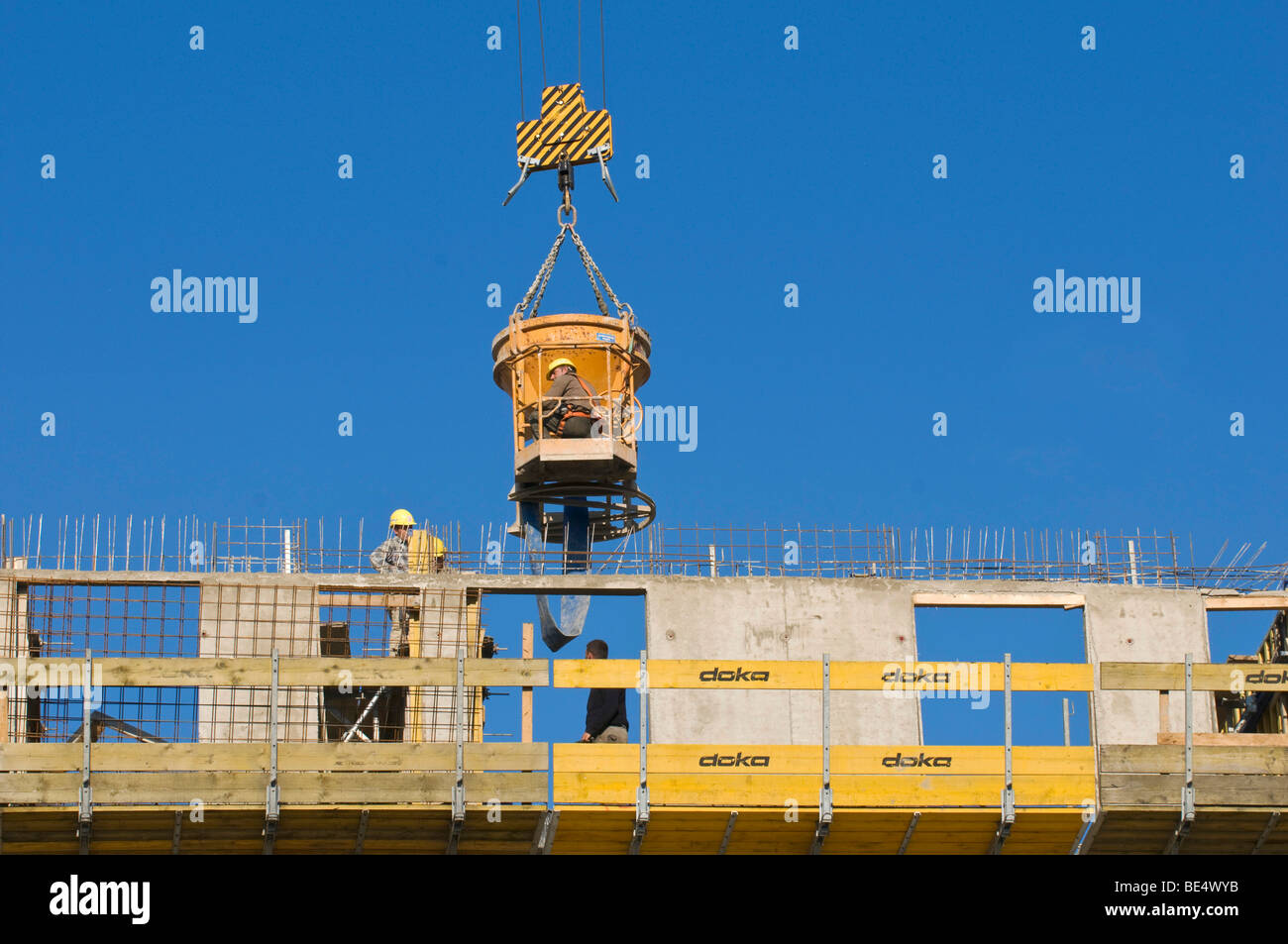 Gießen von Beton auf der Baustelle mit einem konkreten Eimer und Schlauch, Bauarbeiter vor Ort, ausgesetzt an der Spitze der Bewehrung Stockfoto