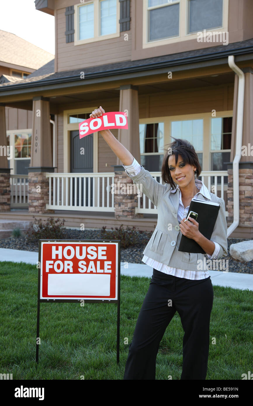 Grundstücksmakler verkauft Zeichen vor Haus hochhalten Stockfoto