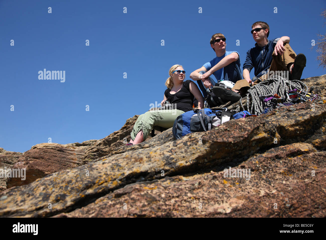Drei junge Erwachsene Zusammensitzen auf Felsen Stockfoto
