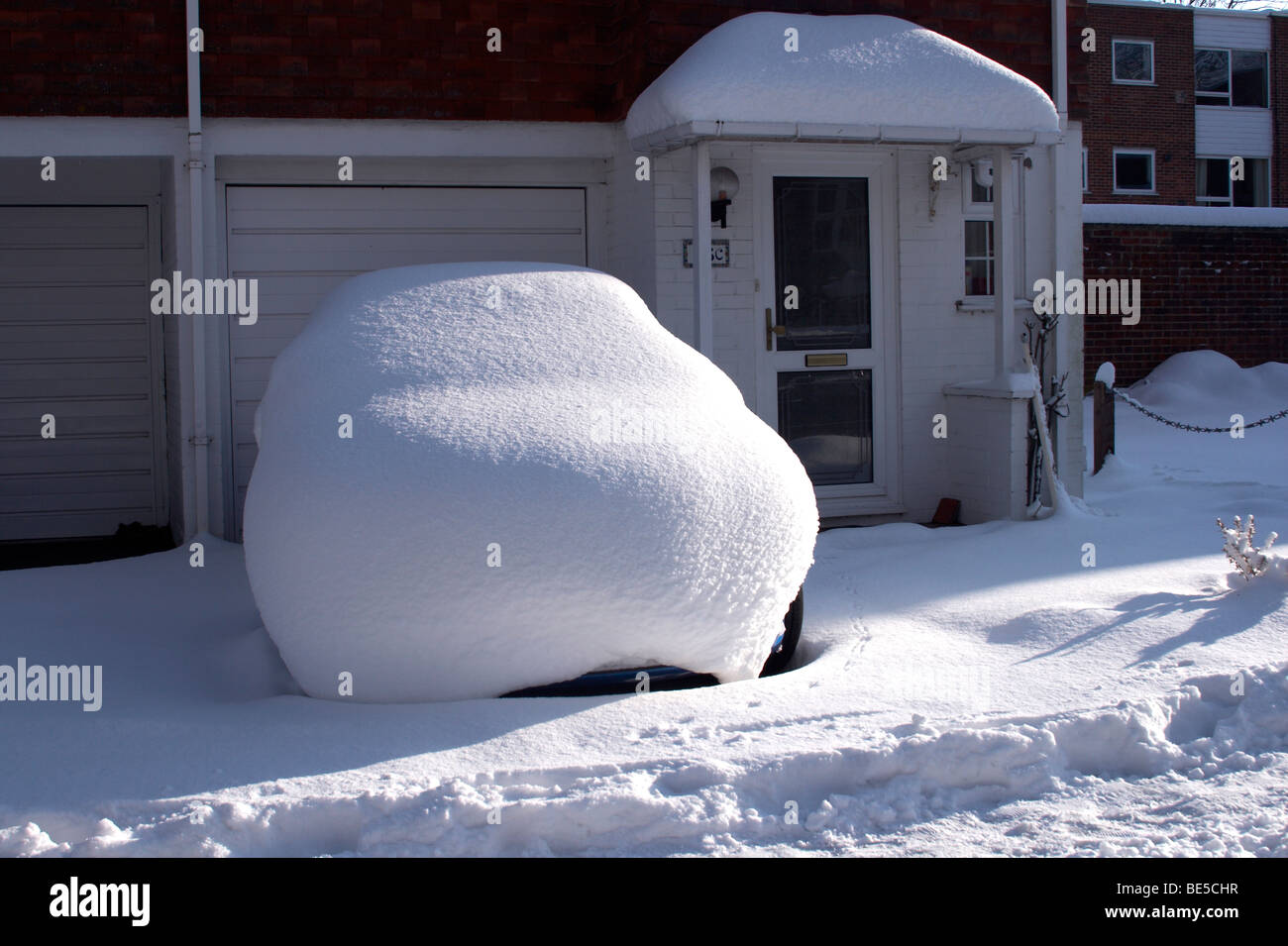 Schneebedeckte Auto auf einer Einfahrt Stockfoto