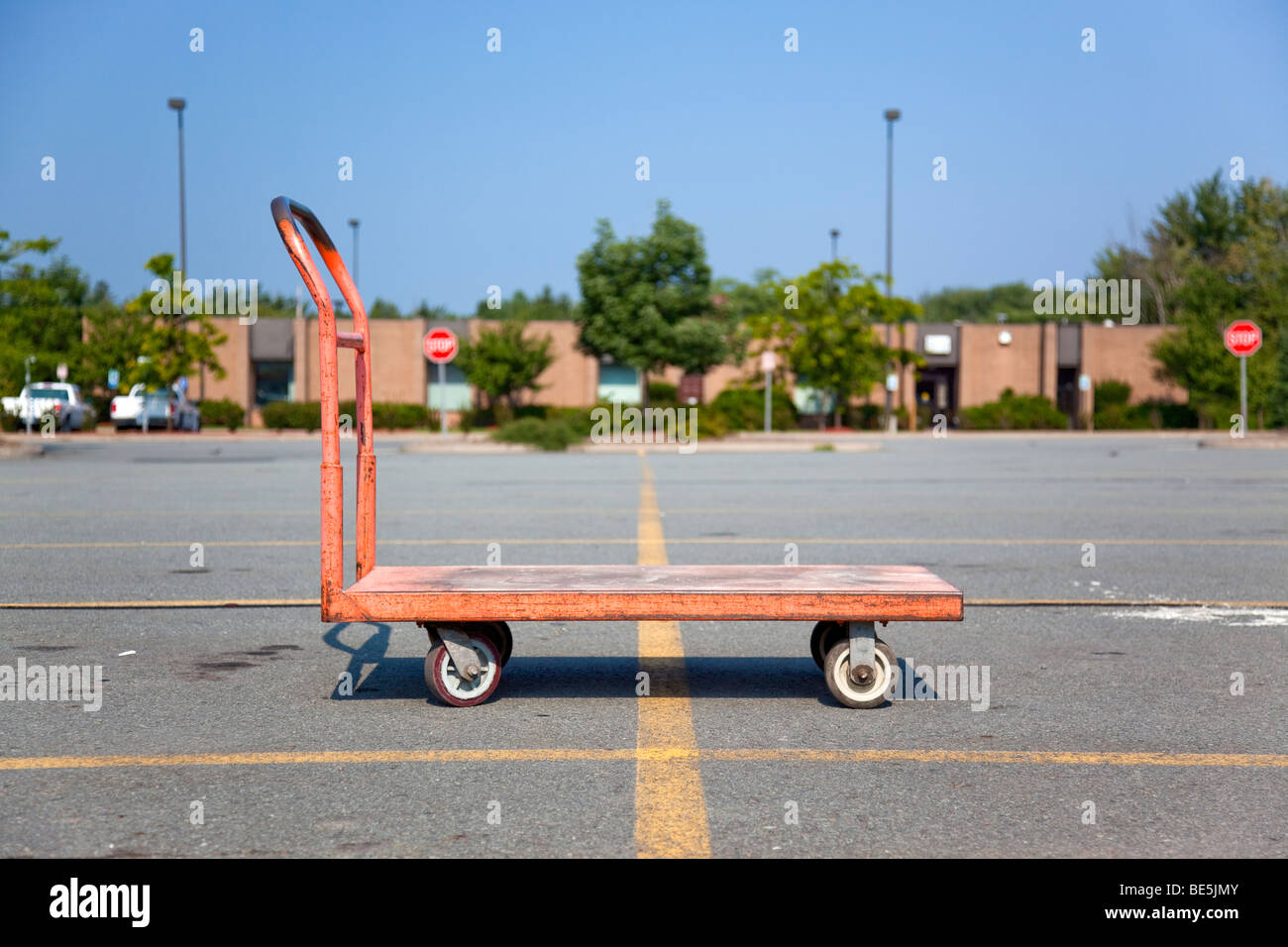 Orange Flachbett-Wagen am Parkplatz ein Geschäft mit Stopp-Schilder und Gebäude im Hintergrund Stockfoto