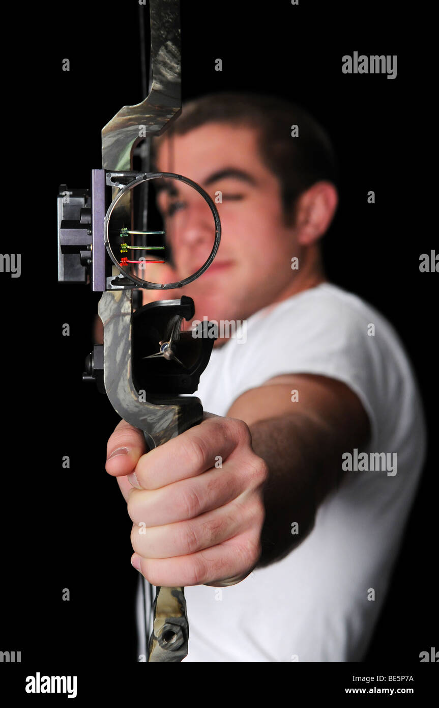 Junger Mann mit Bogen und Pfeil mit dem Ziel direkt über einen schwarzen Hintergrund isoliert. Stockfoto