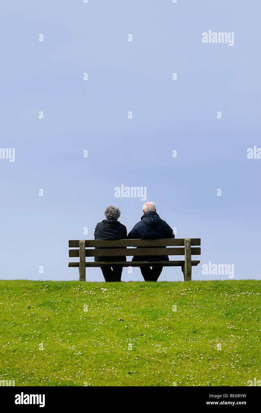 Älteres Ehepaar sitzt auf einer Bank auf dem Deich Stockfoto