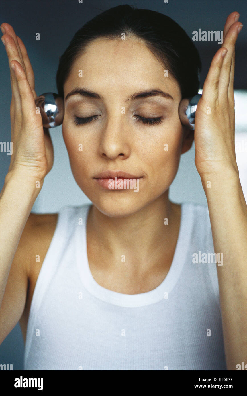 Frau massiert Tempel mit Yin Yang Kugeln Stockfoto